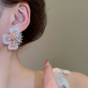 Detailed close-up of a crystal flower earring with colorful rhinestones on a model
