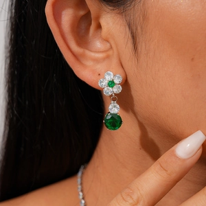 Close-up of a luxury flower earring with emerald green gemstone and sparkling zircons