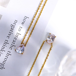 Close-up of gold chain necklace featuring oval and teardrop zircon pendants