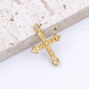 Macro view of gold stainless steel cross pendant with intricate embossed textures