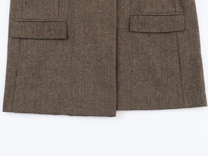 Dettaglio del tessuto marrone a spina di pesce e tasche a patta del blazer casual