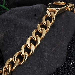 Detail of a golden hip-hop cuban chain bracelet on dark stone texture background