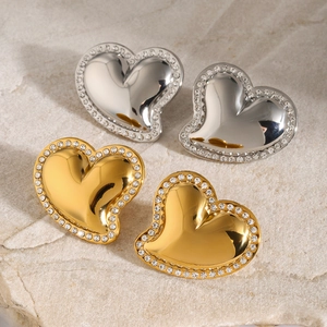 Macro shot of 18k gold and silver heart earrings with inlaid white cubic zirconia stones