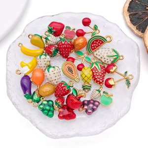 Close-up of assorted enamel fruit pendants including strawberry and cherry for DIY jewelry