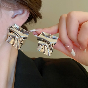 Close-up of irregular pleated silver earring worn by a model showing metallic texture