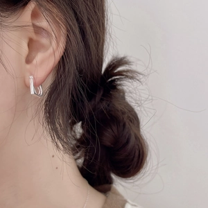Close-up of minimalist square silver hoop earring worn by model in a clean style