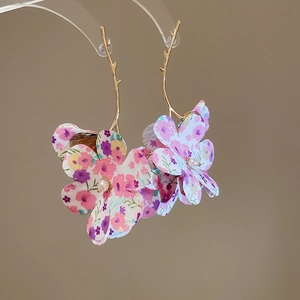 Macro shot of gold branch earrings with colorful floral fabric and small pearls