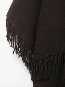 Detailed close-up of dark brown knit texture and tassel fringe on a warm cape poncho