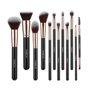 Flat lay of 12 black and rose gold makeup brushes with brown fiber bristles on white background