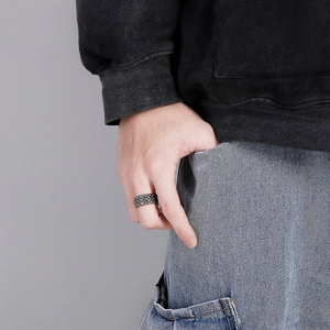 Gros plan d'une bague punk en argent rétro avec texture tressée sur une main d'homme