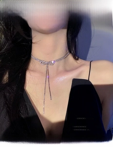 Close-up of sparkling rhinestone bow tassel choker necklace on a model with cool lighting