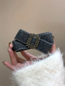 Gros plan d'une pince à cheveux nœud en feutre gris avec boucle en strass pour un style élégant