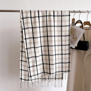 Detail of checkered cashmere-feel scarf with tassels and soft beige wool texture