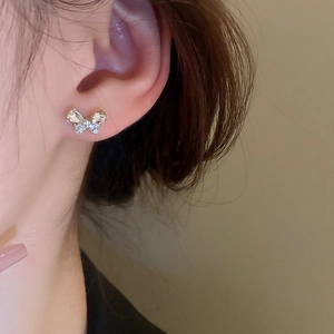 Elegant silver butterfly stud earrings with sparkling diamonds on a female model's ear
