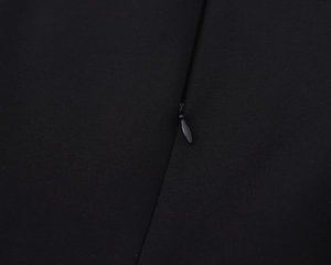 Detailed view of the invisible black zipper closure on a sleeveless bow dress