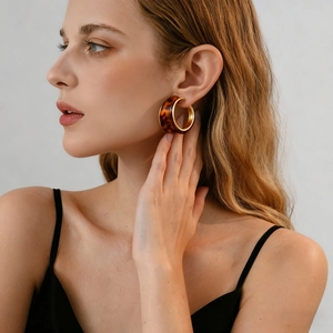 Close-up of tortoise shell resin C-shaped hoop earrings worn by a fashion model
