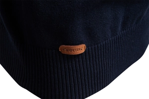 Dettaglio dell'orlo in maglia a coste blu scuro con etichetta logo in pelle marrone pregiata