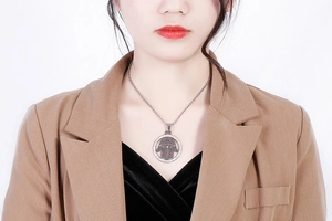 Detailed view of a silver Hamsa Hand pendant on a titanium steel necklace on model