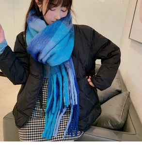 Close-up of blue gradient plaid scarf with long decorative fringe and knit texture