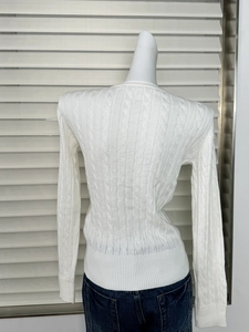 Detail view of the cable knit texture and ribbed hem on the white slim fit sweater