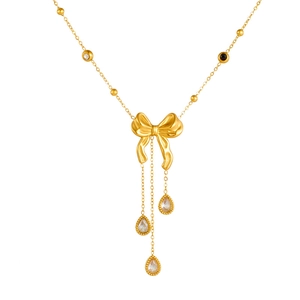 Collier doré avec nœud papillon, pierres noires et blanches et pompons gouttes