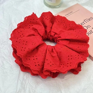 Close-up of red lace scrunchie with intricate embroidery on a minimalist white background