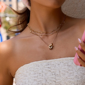 Detalle de collares en capas bañados en oro de 18 quilates con anillos y piedras brillantes