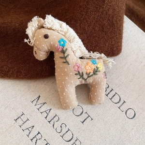 Detail of handmade horse brooch featuring polka dots and exquisite floral embroidery