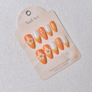 Détail d'ongles amande avec dégradé orange et fleurs 3D sur carte de présentation