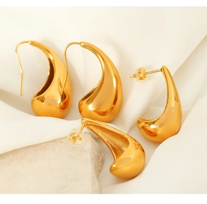Detail of 18K gold plated teardrop earrings on white satin and textured stone