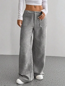 Dettaglio dei pantaloni di velluto a coste grigi a vita alta con grandi tasche applicate