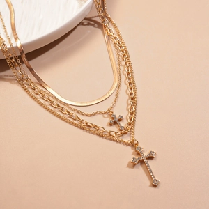 Detail of gold layered necklace featuring crystal cross pendants and snake chain texture