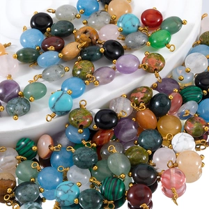 Dettaglio macro di perle in pietra naturale con filo dorato e passanti per DIY