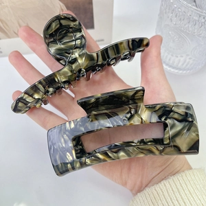 Close-up of large acetate hair claw clips with dark marble and tortoiseshell patterns