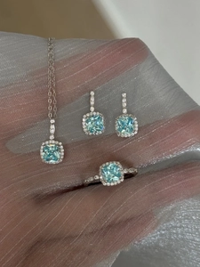Close-up of light blue halo jewelry set with square stones on silver mesh