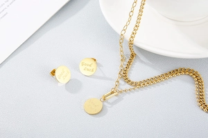 Close-up of a double-layer gold titanium necklace and stud earrings with Good Luck engraving