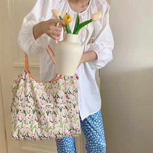 Close-up of floral canvas tote bag held by model with tulips in a soft aesthetic room