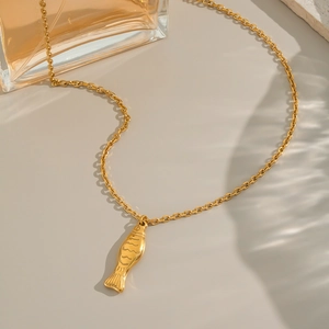 Elegant gold fish pendant necklace set on light background with professional lighting