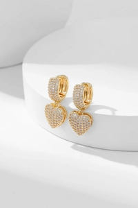 Close-up of gold heart earrings with micro-pave white zircon on a white podium