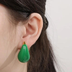 Close-up of a model wearing large green teardrop earrings with gold metal accents