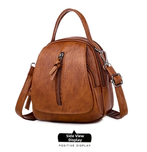 Side view of brown textured leather shoulder bag with tassels and multiple zipper compartments
