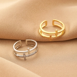 Detail of layered cross rings with crystals and smooth metal on a silk background