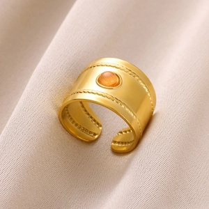 Macro detail of gold open ring with orange cat-eye stone on beige silk fabric