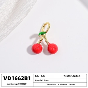 Macro view of gold brass cherry pendant with red fruit and green leaf details
