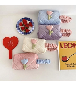 Flat lay of four colorful quilted corduroy cosmetic bags with tulip floral decorations