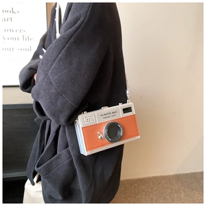 Detailed view of a vintage camera-shaped crossbody bag in silver and orange leather finish