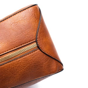 Close-up of brown leather bag featuring golden metal zipper and fine stitching detail