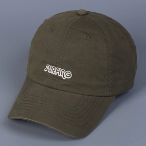 Detail view of white SURFING embroidery on a dark green washed cotton baseball cap