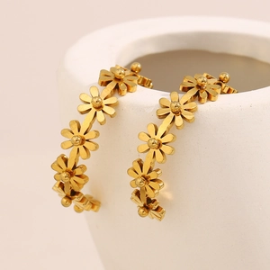 Vue macro des boucles d'oreilles marguerites plaquées or 18K sur un support blanc