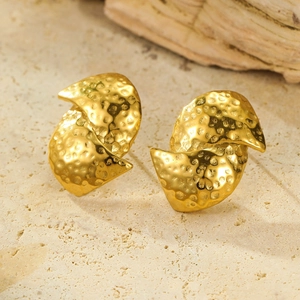Macro detail of 18K gold-plated earrings with unique hammered metal texture and wavy design